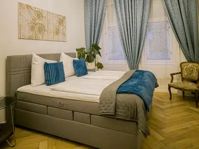 a bedroom with a large bed with blue curtains at Rose Essence Suite in Prague