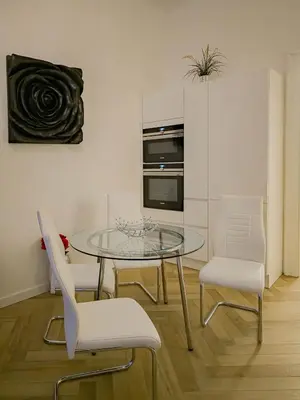 a dining room with a glass table and white chairs at Rose Essence Suite in Prague