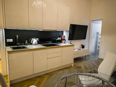 a kitchen with white cabinets and a flat screen tv at Rose Essence Suite in Prague