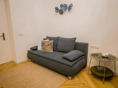 a grey couch in a living room with a table at Rose Essence Suite in Prague