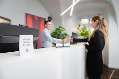 a man and a woman shaking hands at a counter at Old Royal Post Boutique Hotel & Premium Suites in Prague