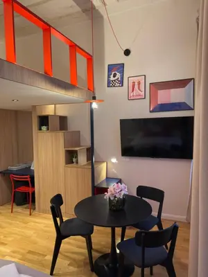 a living room with a table and chairs and a tv at Heritage Haven Mezzanine Apartment with Balcony in Prague