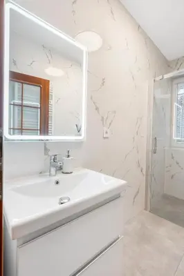 a white bathroom with a sink and a mirror at The Dante House Šeberov in Prague