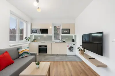 a living room with a gray couch and a kitchen at The Dante House Šeberov in Prague