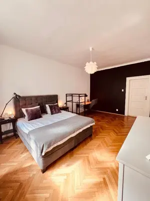 a bedroom with a large bed and wooden floors at Elegant & inviting entire flat on Letná in Prague