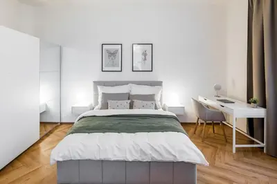 a white bedroom with a bed and a desk at Modern apartment in the center of Prague in Prague