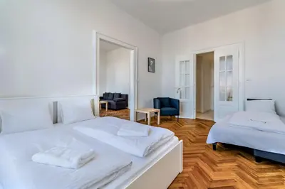 a white bedroom with two beds and a living room at Grand Old Town Suites in Prague
