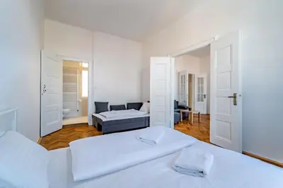 a white bedroom with two beds and a couch at Grand Old Town Suites in Prague