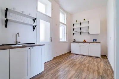 a kitchen with white cabinets and a wooden floor at Grand Old Town Suites in Prague