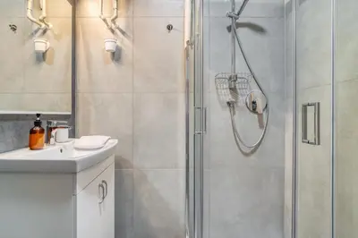 a shower with a glass door next to a sink at Cozy Corner Sokolská by Rentez in Prague