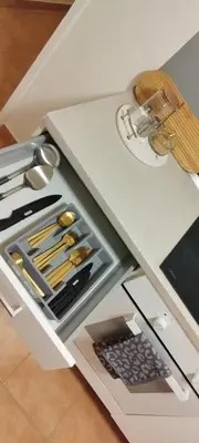 a white counter with a drawer full of knives at Quiet Apartment Near Prosek Metro, Line C in Prague