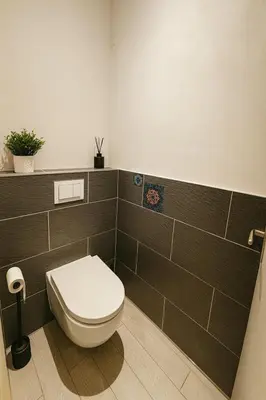 a bathroom with a white toilet and brown tiles at Exclusive Apartment with Terrace, View & Jacuzzi in Prague