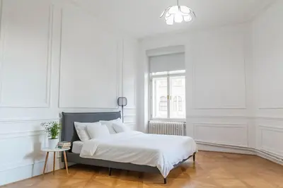 a white bedroom with a bed and a window at Spacious APT by Wenceslas Square & National Museum in Prague