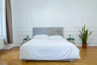 a white bed in a white bedroom with two tables at Spacious APT by Wenceslas Square & National Museum in Prague