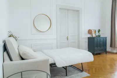 a white living room with a white chair and a mirror at Spacious APT by Wenceslas Square & National Museum in Prague
