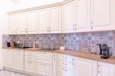 a white kitchen with white cabinets and blue tiles at Spacious APT by Wenceslas Square & National Museum in Prague