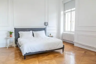 a white bedroom with a bed with white sheets and pillows at Spacious APT by Wenceslas Square & National Museum in Prague