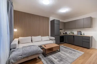 a living room with a white couch and a kitchen at Prague Family Apartment in Prague
