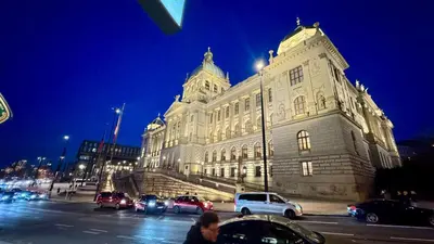 a large building with cars parked in front of it at Night next to the Museum in Prague