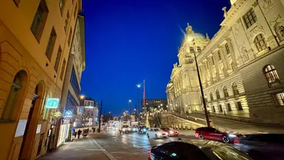 a city street at night with cars and buildings at Night next to the Museum in Prague