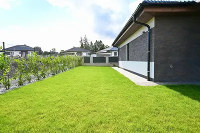 a house with a patio and a green lawn at Pool & Relax Mukařov in Srbín