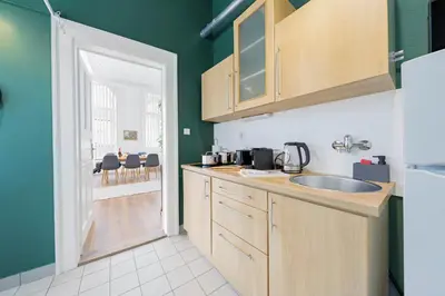 a kitchen with green walls and wooden cabinets and a sink at Cozy Central Two-Bedroom Apartment in Prague