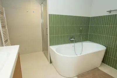 a bath tub in a bathroom with green tile at Prague City Center 99m2 Andel Family Apartment for 6 Bath and Shower Self Check in in Prague