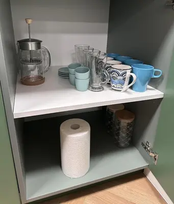 a shelf with cups and plates and a roll of toilet paper at Prague City Center 99m2 Andel Family Apartment for 6 Bath and Shower Self Check in in Prague