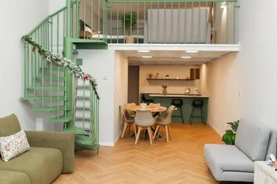 a living room with a table and a green staircase at Prague City Center 99m2 Andel Family Apartment for 6 Bath and Shower Self Check in in Prague