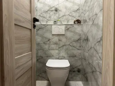 a bathroom with a toilet and a marble wall at Spacious 3BR Apartment near Metro in Prague