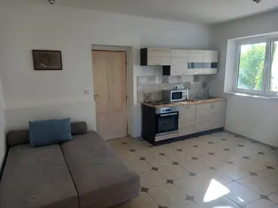 a living room with a couch and a kitchen at Ubytováni U rybníčku in Bzová