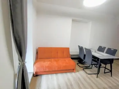 an orange couch in a room with a table and chairs at 2 - room apartment with terrace and free parking in Prague