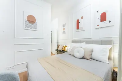 a bedroom with a bed with white walls and artwork at Rentero Central Apartment near Charles Square in Prague