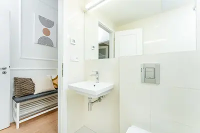 a white bathroom with a sink and a mirror at Rentero Central Apartment near Charles Square in Prague