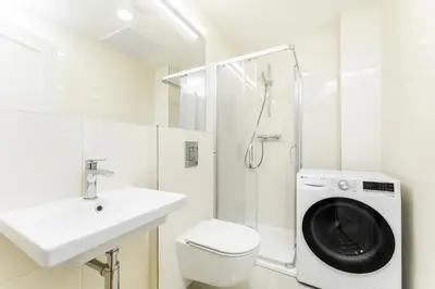 a white bathroom with a sink and a washing machine at Rentero Central Apartment near Charles Square in Prague