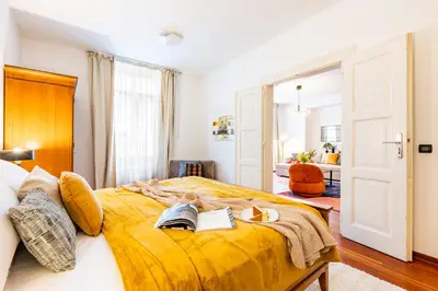 a bedroom with a yellow bed with a book and books at Prague Days - Three Bedroom Apartment with AC, Desk and 100Mbs WiFi in New Town in Prague