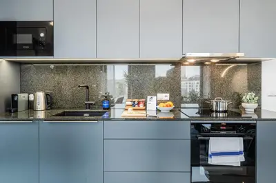 a kitchen with white cabinets and a counter top at Prague Days - Two Bedroom Apartment with Garage, AC, Terrace and Balcony in Vinohrady in Prague