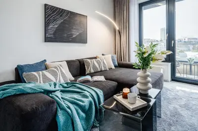 a living room with a couch and a large window at Prague Days - Two Bedroom Apartment with Garage, AC, Terrace and Balcony in Vinohrady in Prague