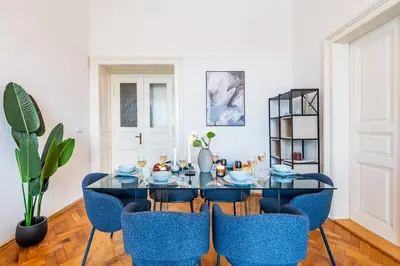 a dining room with a table and blue chairs at Prague Days - Riverside Two-Bedroom Apartment with Workspace in New Town in Prague