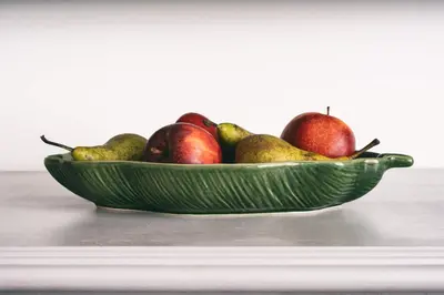 a green bowl of apples and pears on a table at Boutique Apartment by KODA Architekt in Prague