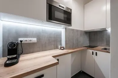 a kitchen with white cabinets and a phone on a counter at Klidný byt v centru se saunou in Prague