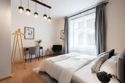 a white bedroom with a large window and a table at Klidný byt v centru se saunou in Prague