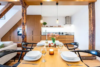 a dining room with a wooden table and chairs at Prague Days - Two Bedroom Riverside Apartment with Gramophone in Prague