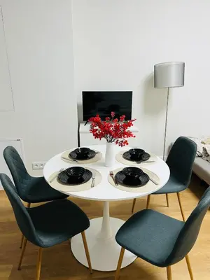 a white table with chairs and a vase with red flowers at Quiet Apartment Farmers' Saturday Market in Prague