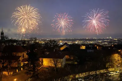 a group of fireworks exploding in the sky over a city at Panoramic top floor flat across the metro in Prague