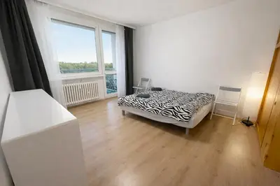 a bedroom with a bed and a large window at Panoramic top floor flat across the metro in Prague