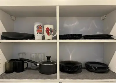 a shelf with two cups and plates and utensils at Panoramic top floor flat across the metro in Prague