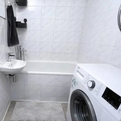 a bathroom with a washing machine and a sink at Panoramic top floor flat across the metro in Prague