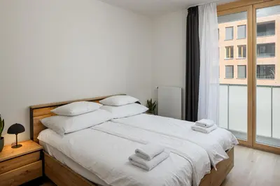 a bedroom with a bed with white sheets and a window at Modern City Apartment in Prague
