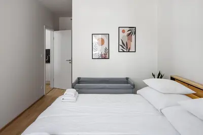 a white bedroom with a bed and a couch at Modern City Apartment in Prague